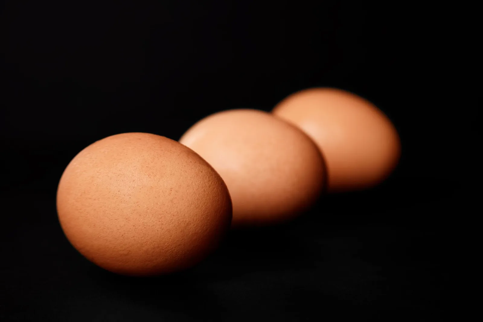 Tres huevos de gallina sobre un fondo negro
